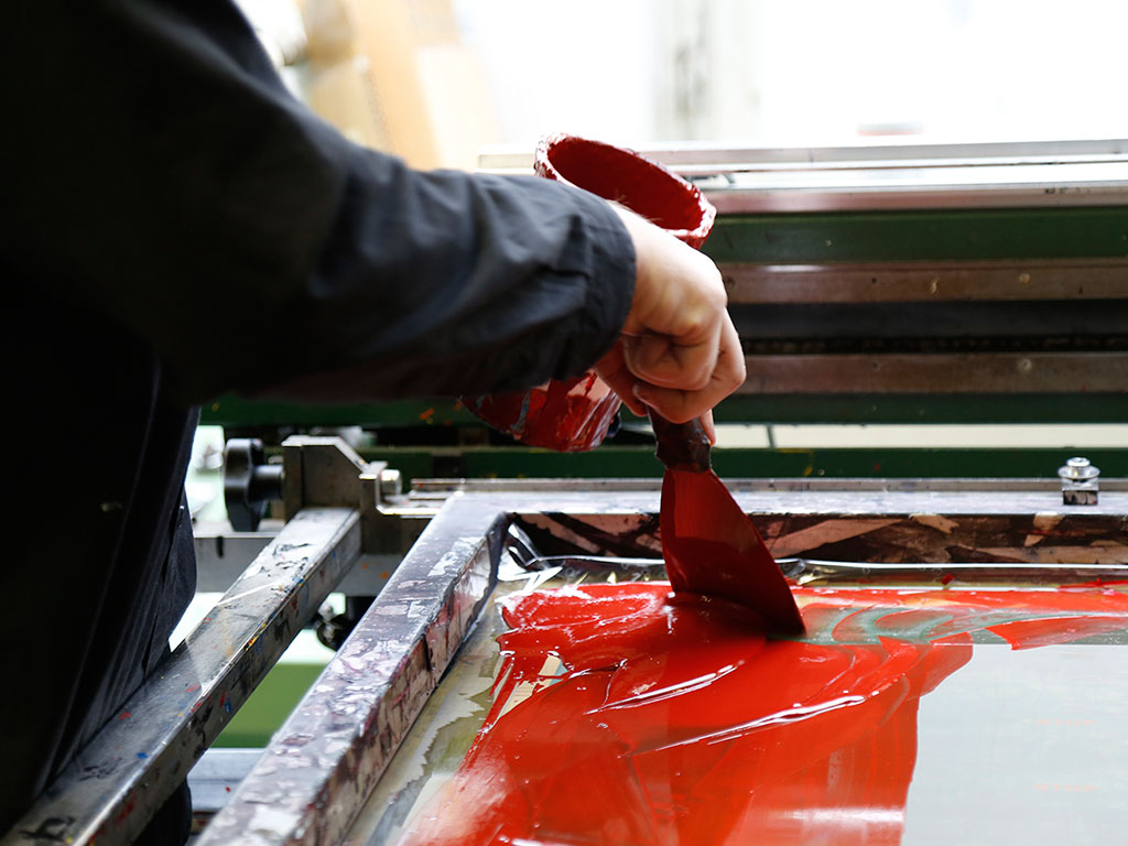 Rote Siebdruckfarbe wird auf das Sieb gegeben